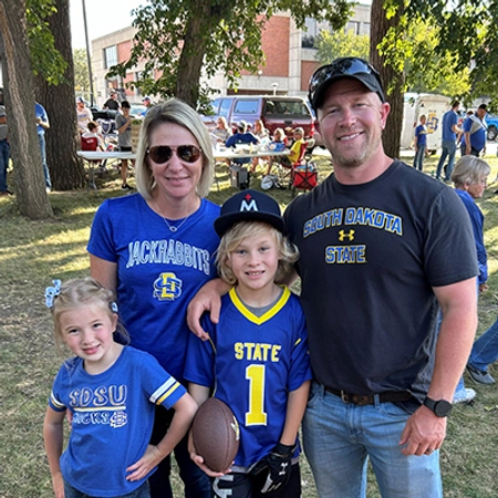 Annie Hanson and her family smiling together at a SDSU tailgate event