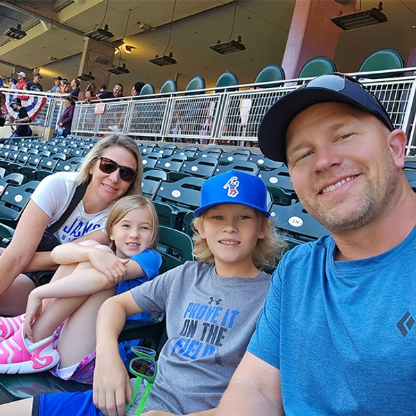 Annie Hanson and her family smiling together in the stands of a baseball game