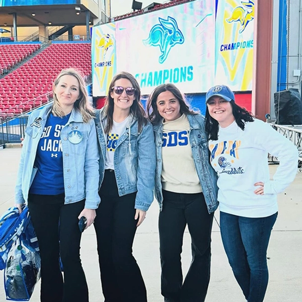Kayla Schinkel stands smiling with three other women after the FCS championship game