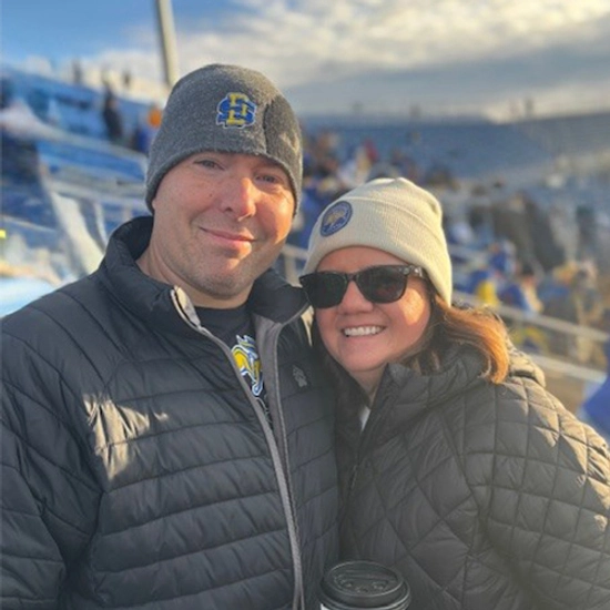 Lindsey Davis and her husband smile together at an SDSU Football game.