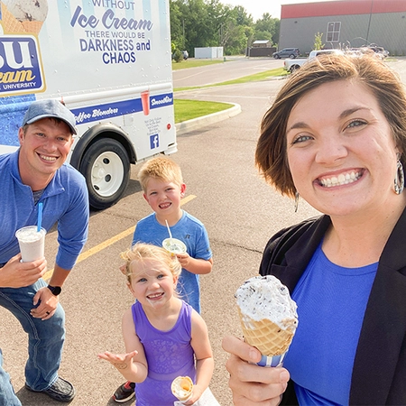 Shelby Hartung and her family next to the SDSU ice cream truck holding ice cream treats