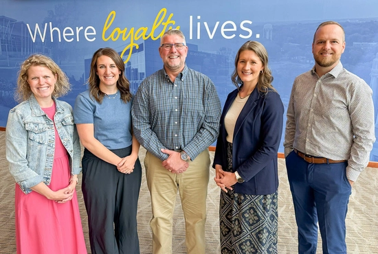 Five SDSU Alumni & Foundation employees stand side by side smiling, with a "Where loyalty lives" graphic behind them.