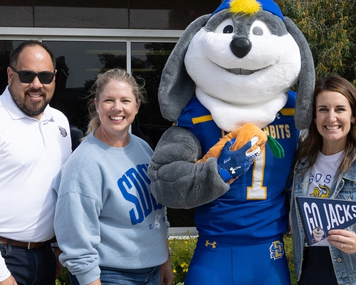 5 members of the SDSU Alumni & Foundation team smile together with Jack the Jackrabbit