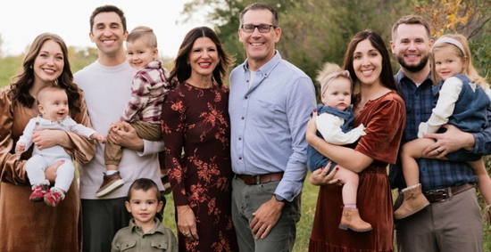 A cheerful photo of the Chambers family posing outdoors in the fall.