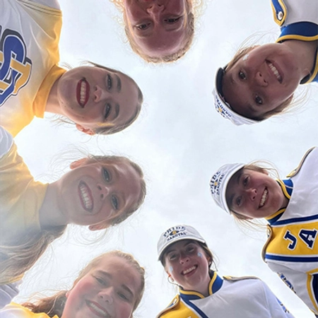 Hannah Hank and a group of friends smile for a camera that is below them.