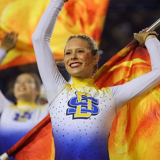 Hannah Hank performs a routine with a yellow and orange flag.
