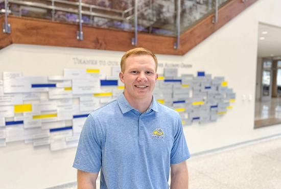 Kole Hawkins smiles standing in a bright atrium space.