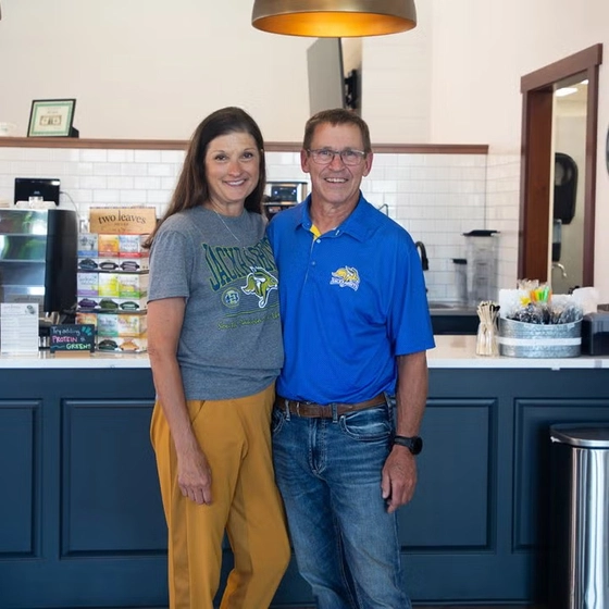 Susan and Mark Leddy smile together standing in their coffee shop in Milbank.