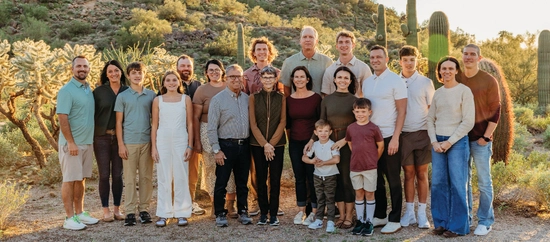 Ramsdell family smiling and standing close together in a desert landscape with cacti and hills.