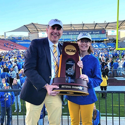 A photo of Kevin Kessler and his wife holding the NCAA National Football Championship trophy.