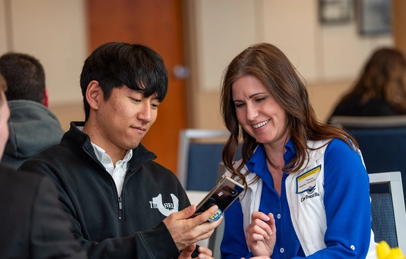 Vanessa Klemme VanDeWiele and Daewon Kim sit together at the culmination event, smiling and looking at a phone.