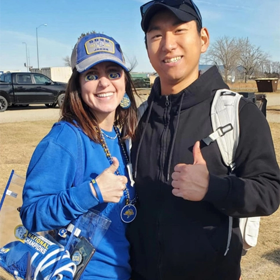 Vanessa Klemme VanDeWiele and Daewon Kim smile and give a 'thumbs up' at an SDSU football tailgate.