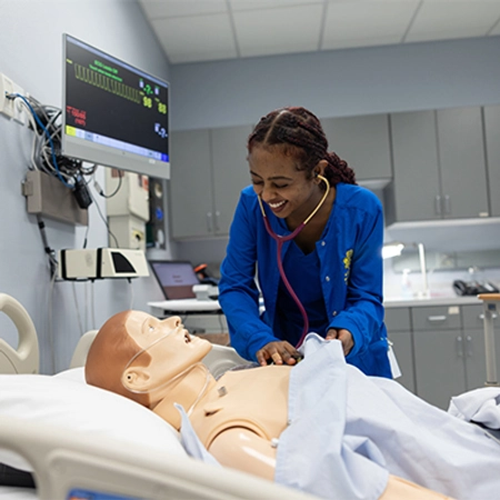 Female nursing student practicing listening to the heart on a simulation mannequin