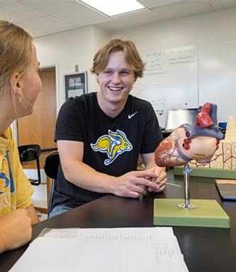 Two students sitting with an anatomy model in a lab