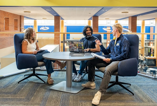 Group of three SDSU students sitting at a table talking with one another.