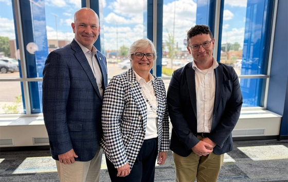 Dr. Dennis Hedge, Dr. Mary Anne Krogh, and Dr. Dan Hansen stand together smiling in the SDSU Metro Center.